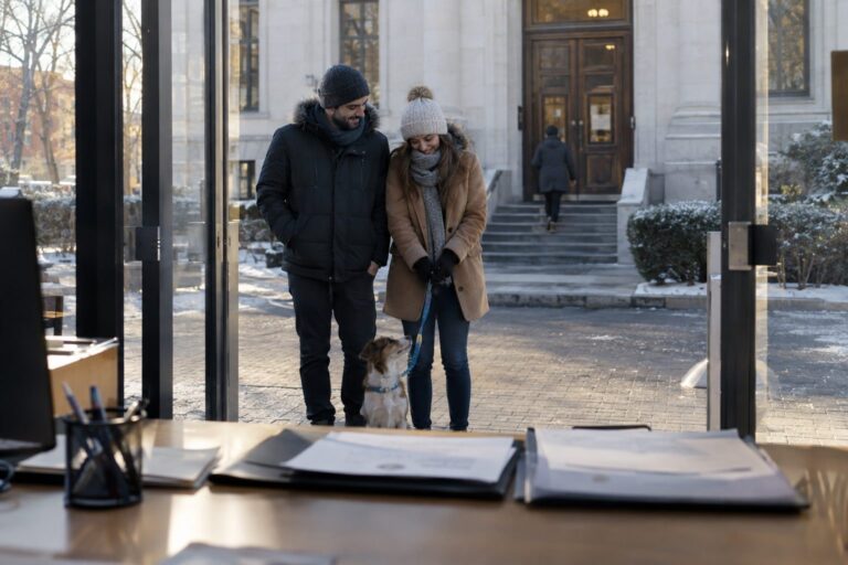 Un couple tenant un chiot en laisse devant une mairie ou un bâtiment administratif, avec des documents officiels visibles sur une table, symbolisant les démarches bureaucratiques pour adopter un chien en 2026