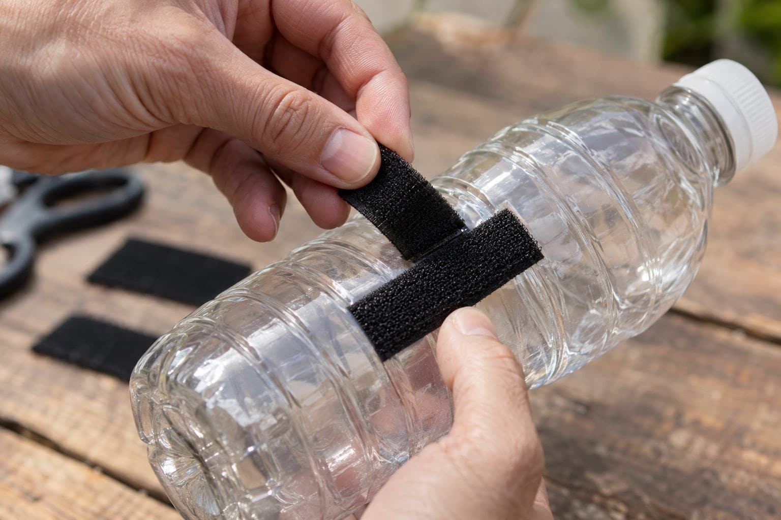 Gros plan d'une main attachant du velcro sur une bouteille en plastique